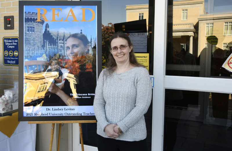 Dr. Lindsey Levitan, , Shepherd University 2021 Outstanding Teacher and associate professor of psychology, poses with the READ poster she's featured on.