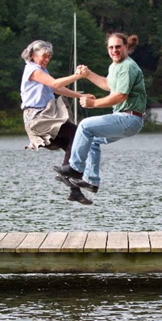 Dancers Kim Forry and Jan Scopel leaping in the air holding hands.