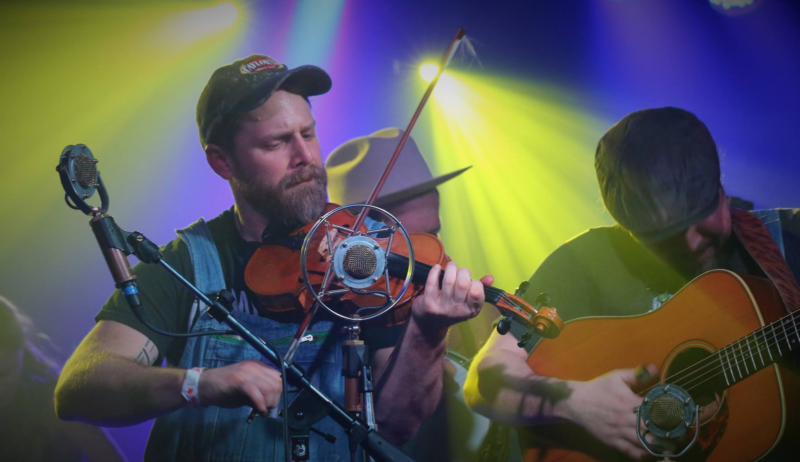 WV musician Ben Townsend plays fiddle in front of a microphone 