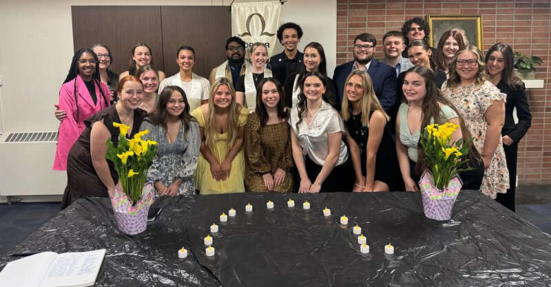 Members of Order of Omega Greek Honor society smile in a group photo after initiation