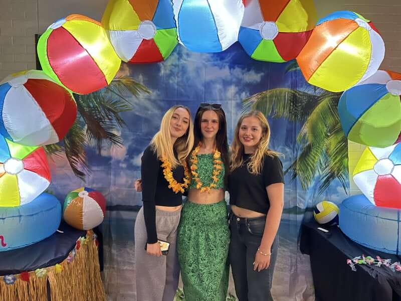 Members of a sorority smile in front of a beach themed background