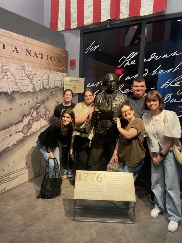 Group of people standing in front of a statue.