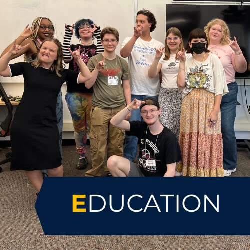Group of students with a professor holding up the ram symbol with their hands.