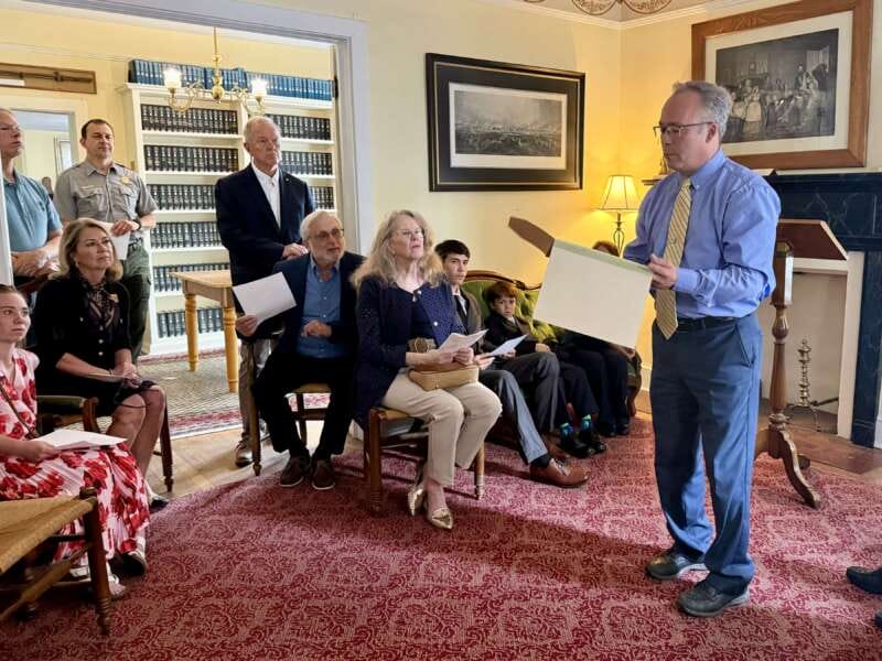Shepherd University alumnus Michael Folk speaks during a dedication ceremony at the George Tyler Moore Center for the Study of the Civil War while holding a framed 1858 letter written by abolitionist John Brown. Family members and guests listen from the audience.