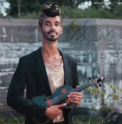 Artist Jake Blount wears a headwrap and suit jacket and holding a fiddle