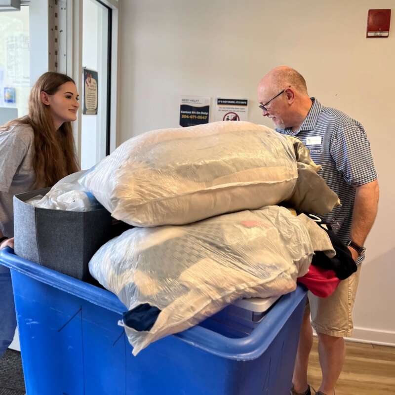 Shepherd University President Dr. Cameron B. Wesson assists a student during residence hall move-in day, helping transport belongings into campus housing at the start of the academic year in Shepherdstown, West Virginia.