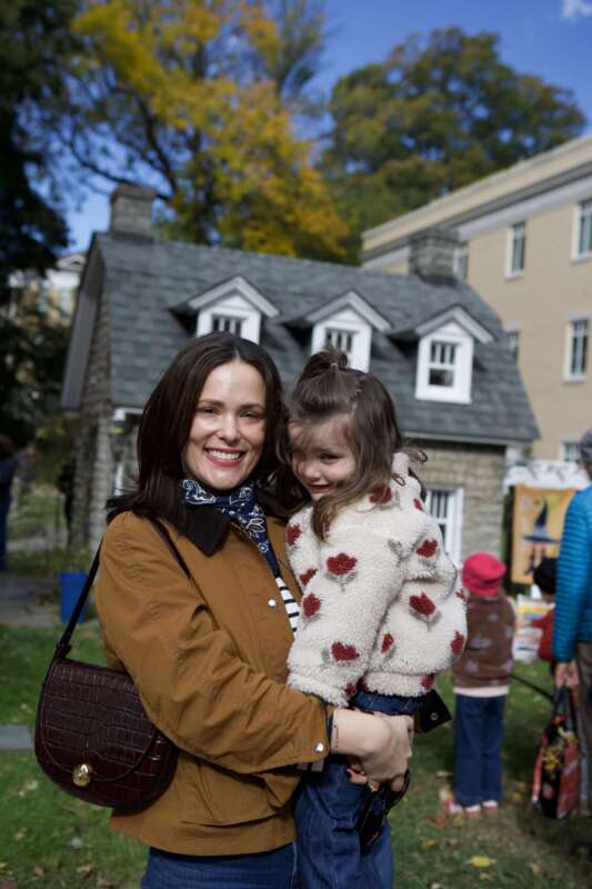 Shepherd University alumna Alex Lemley holding a young child outdoors during a fall event.